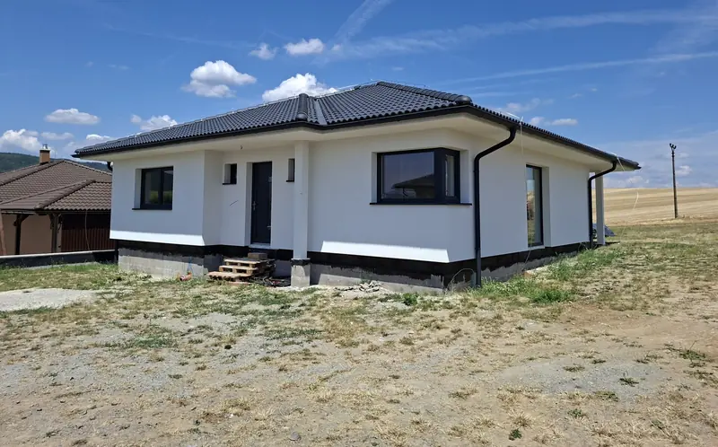 Zateplený a omietnutý bungalov s tmavou škridlovou strechou