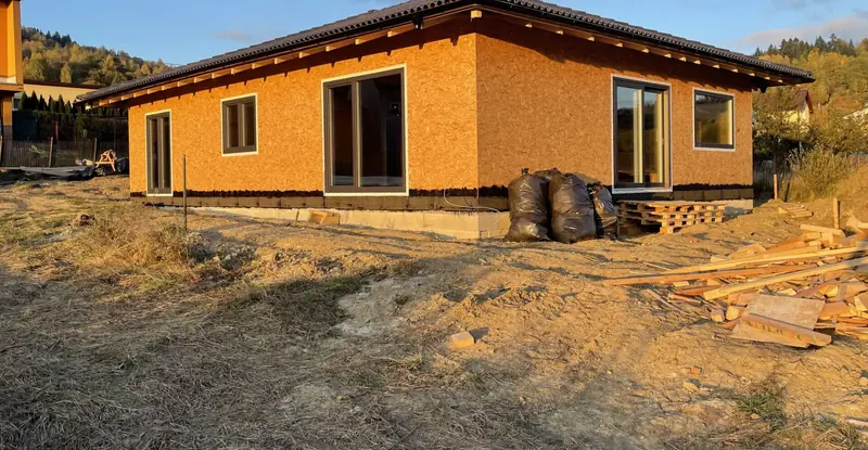 Hrubá stavba bungalovu opláštená OSB doskami so strechou a oknami